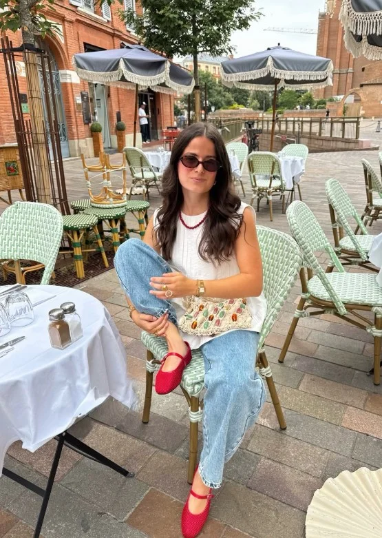 Woman in light jeans with a simple neutral top and red ballet flats