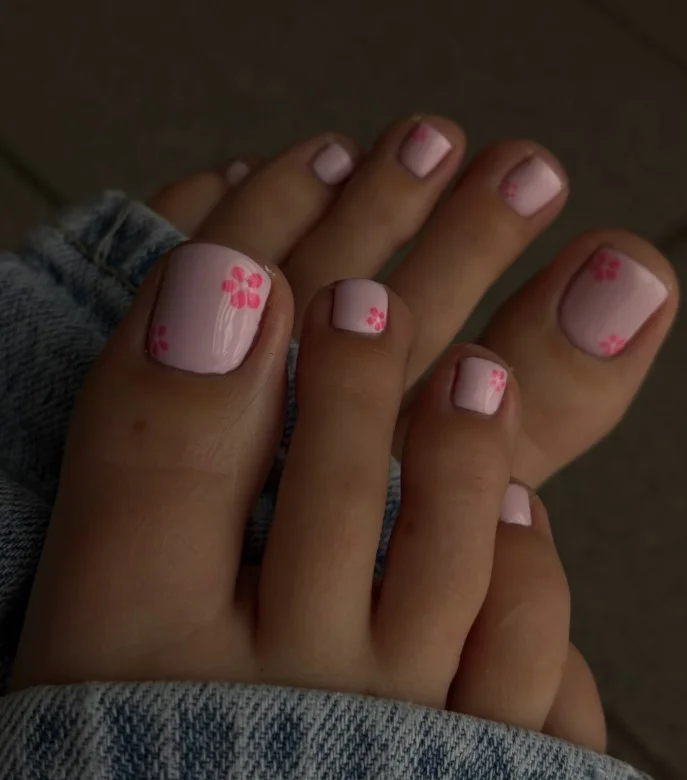 Soft pink toenails decorated with delicate white floral details