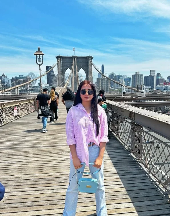 Woman in light jeans with a soft pink cardigan and neutral flats