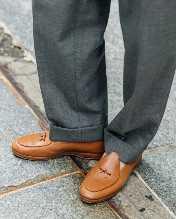 Tan leather brogues complementing light grey pants for a smart-casual look.