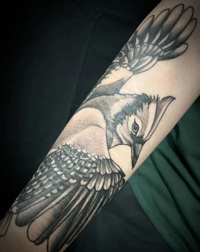 Several birds in flight extending around a woman's forearm in a delicate nature-inspired tattoo