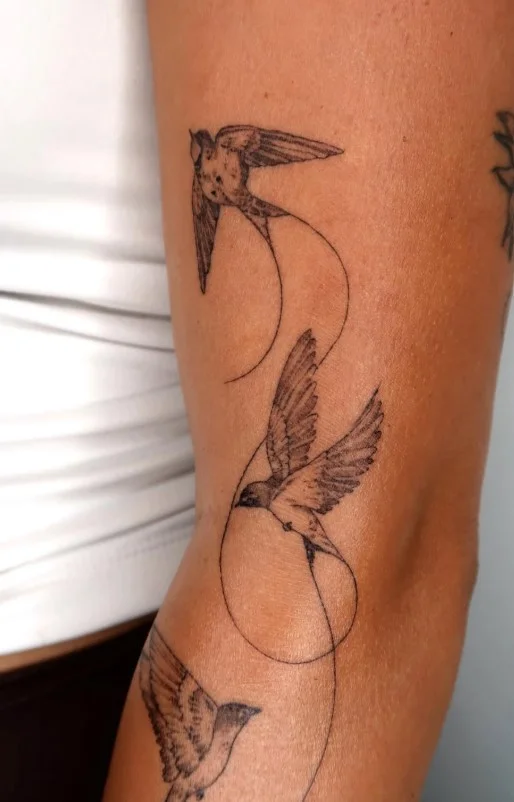 Birds in flight wrap around arm tattoo with birds spaced naturally around the arm
