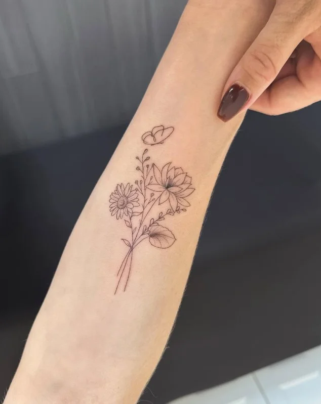 Delicate birth flower tattoo with a slender stem on the inner forearm