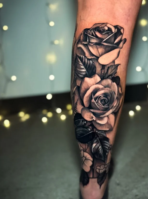 Black-and-grey floral calf tattoo with detailed shaded petals