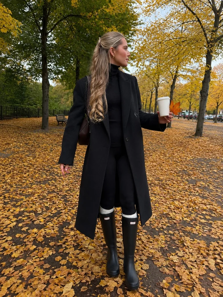 Black turtleneck leggings long coat and Hunter boots