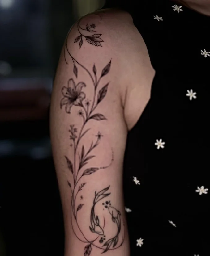 Blackwork botanical bicep wrap tattoo with bold fern fronds and dark leaves