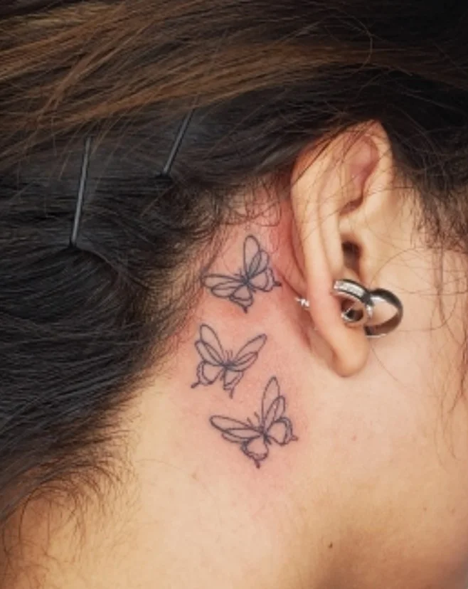 Delicate butterfly tattoo behind the ear for women
