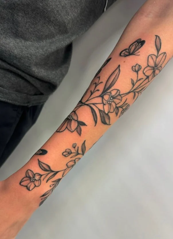 Butterfly and floral wrap around arm tattoo with flowers and delicate stems