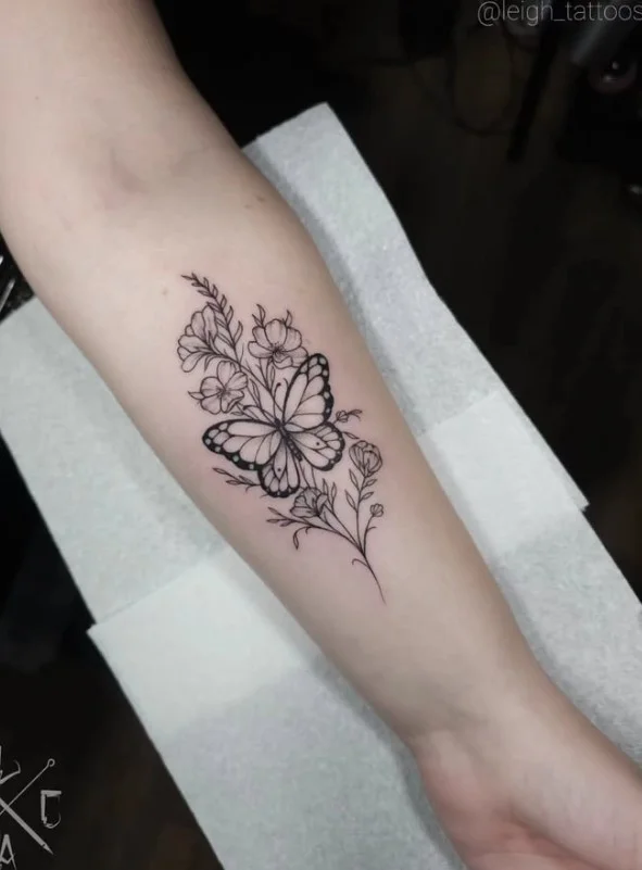 Fine-line butterfly and flower tattoo arranged on the inner forearm