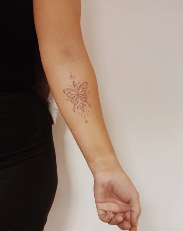Delicate butterfly forearm tattoo with detailed wings and fine-line detailing