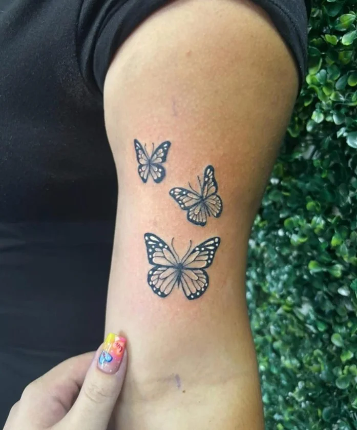 Butterfly upper arm tattoo idea with a delicate feminine design