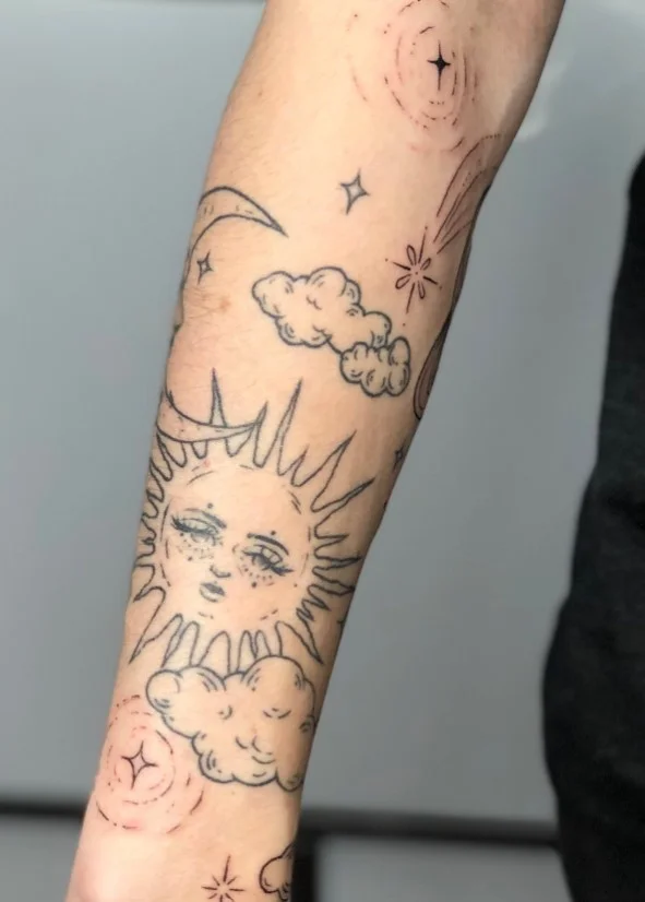 Sun and crescent moon with decorative stars in a celestial wrap around forearm tattoo