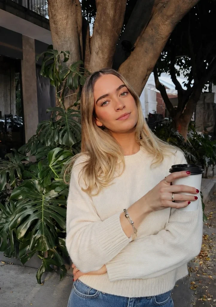 Woman wearing a Pandora bracelet with a cream sweater and straight-leg jeans