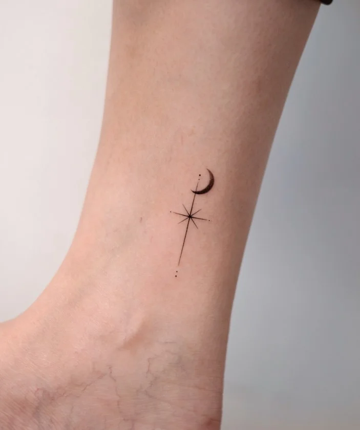 Small ankle tattoo featuring a crescent moon and several tiny stars in a delicate minimalist design