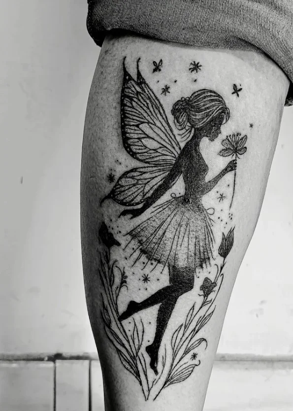 Dark fairy tattoo with flowing wings on a woman's lower leg