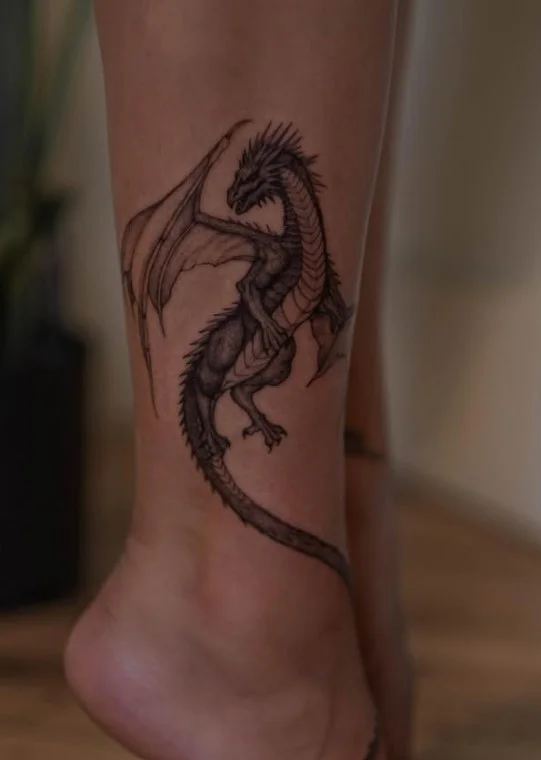 Elegant dragon flowing vertically along a woman's lower leg