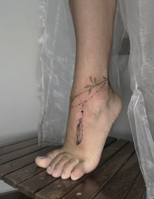 Fine line ankle bracelet tattoo featuring a delicate minimalist band wrapping naturally around the ankle
