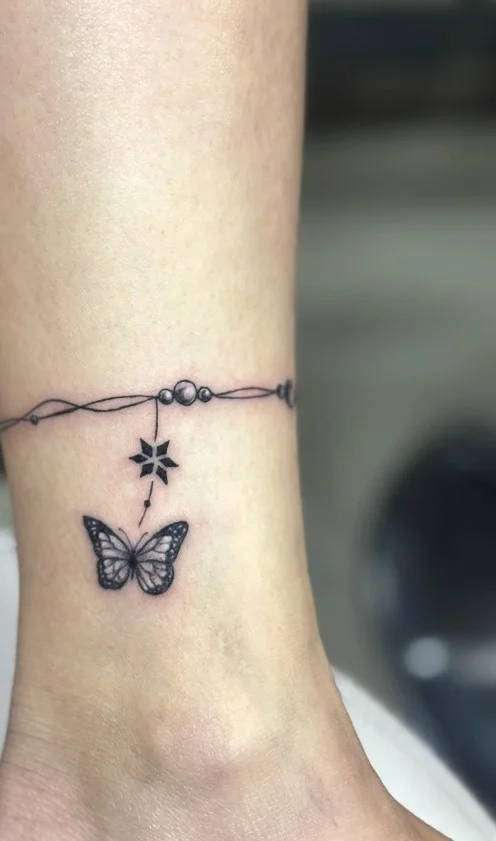 Fine line butterfly ankle tattoo featuring a small delicate butterfly with detailed outlined wings above the ankle bone