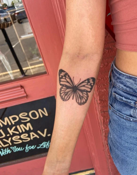 Fine-line butterfly tattoo with detailed wings on the inner forearm