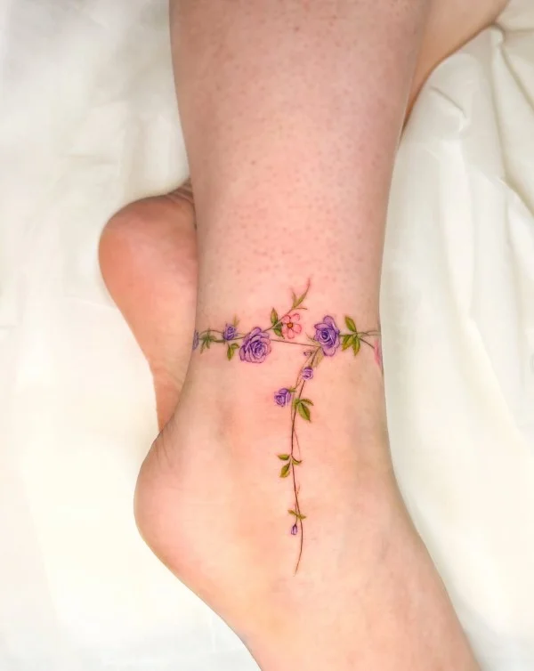 Fine line floral ankle tattoo featuring a delicate outlined flower with a slender botanical stem above the