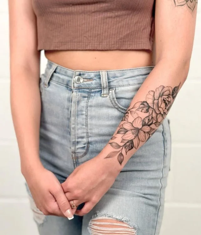 Delicate fine-line floral forearm tattoo with slender stems and detailed flowers