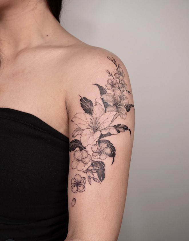 Fine-line floral upper arm tattoo with delicate black ink details