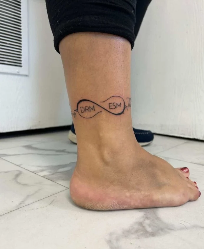 Fine line initial ankle tattoo featuring a single minimalist letter in delicate lettering on the inner ankle