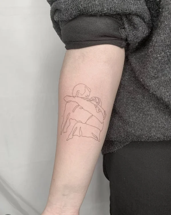 Fine-line portrait tattoo featuring a detailed face on the inner forearm