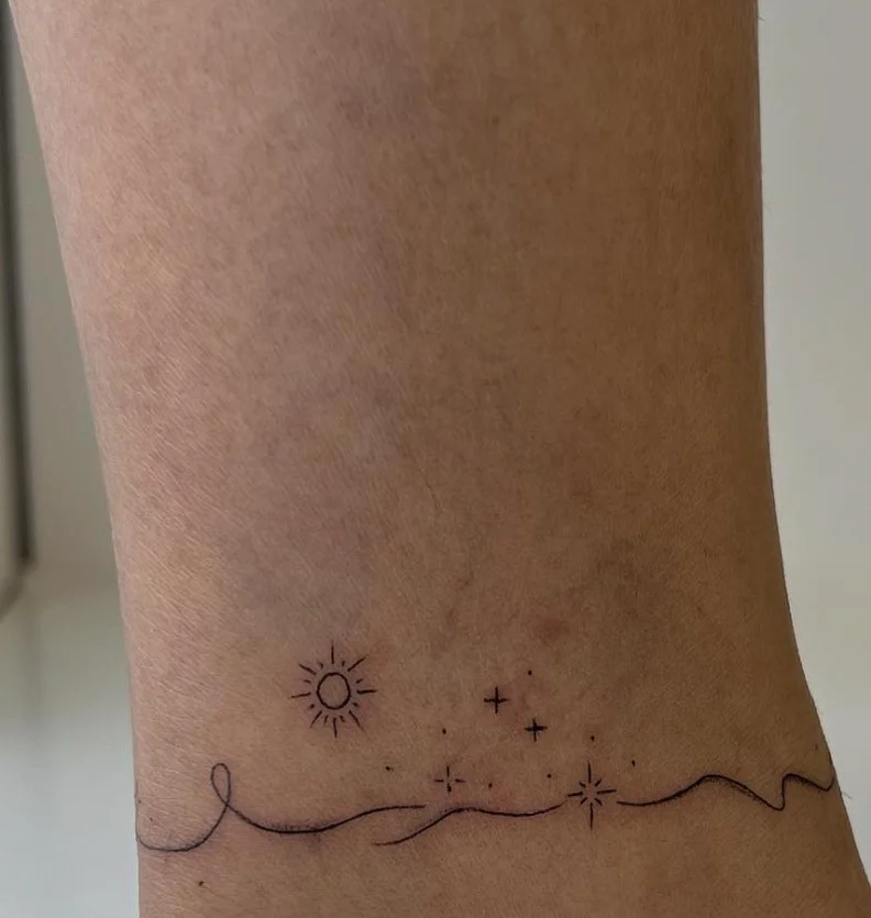 Fine line wave ankle tattoo featuring a single delicate flowing line inspired by an ocean wave on the outer ankle