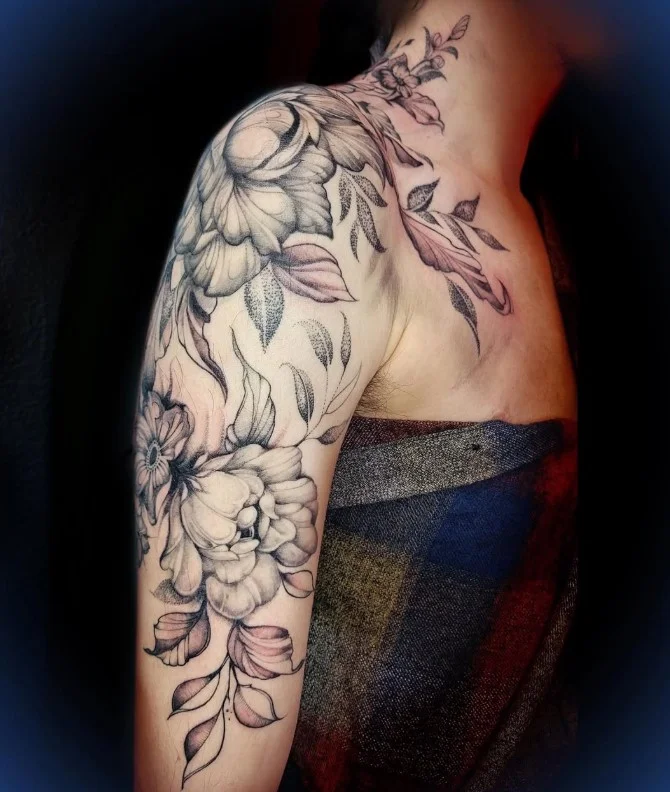 Floral upper arm half-sleeve tattoo with flowers and flowing leaves