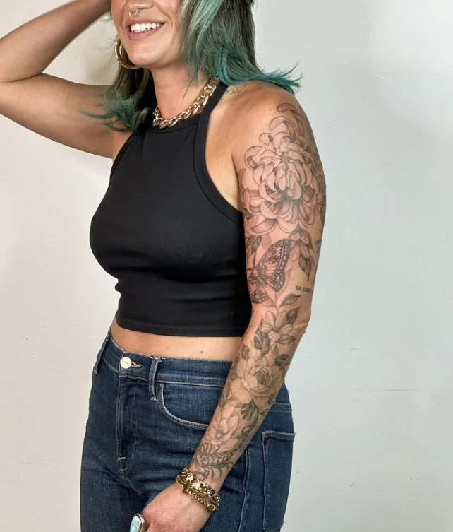 Floral upper arm tattoo idea for women with a delicate feminine flower design