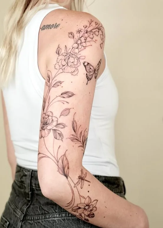 Flowering vine and leaf wrap around arm tattoo with delicate botanical details