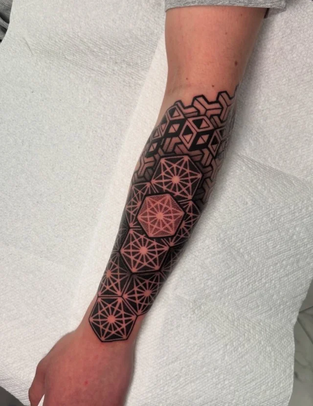 Geometric forearm tattoo featuring symmetrical shapes, clean lines, and precise patterns