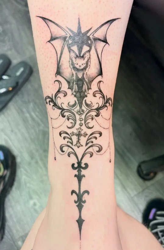 Gothic bat with ornamental details in a woman's calf tattoo