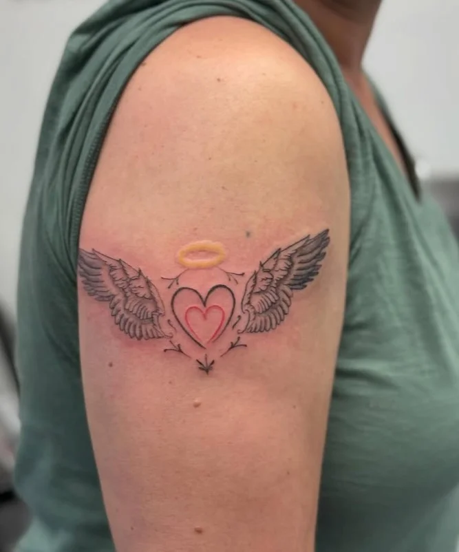 Simple heart upper arm tattoo with a feminine minimalist design