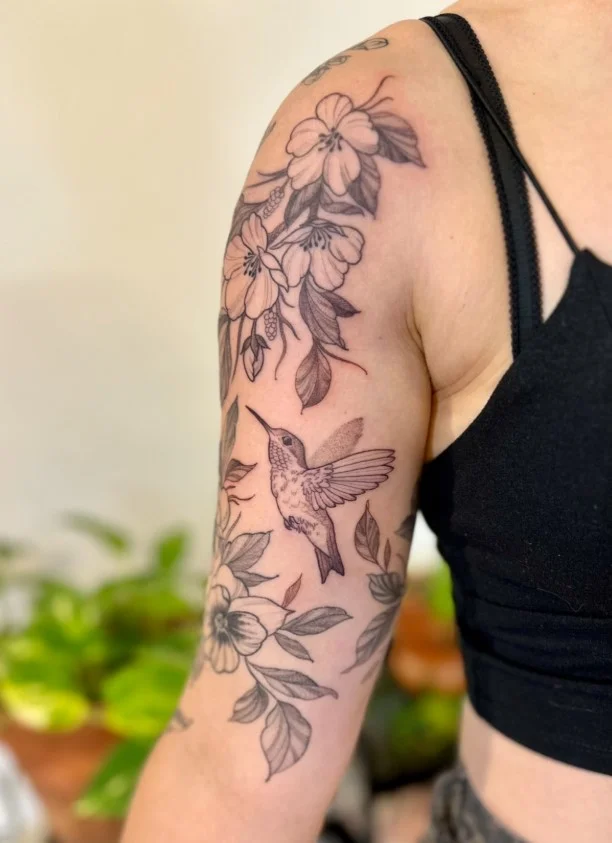 Hummingbird and flower upper arm tattoo with a graceful nature-inspired design
