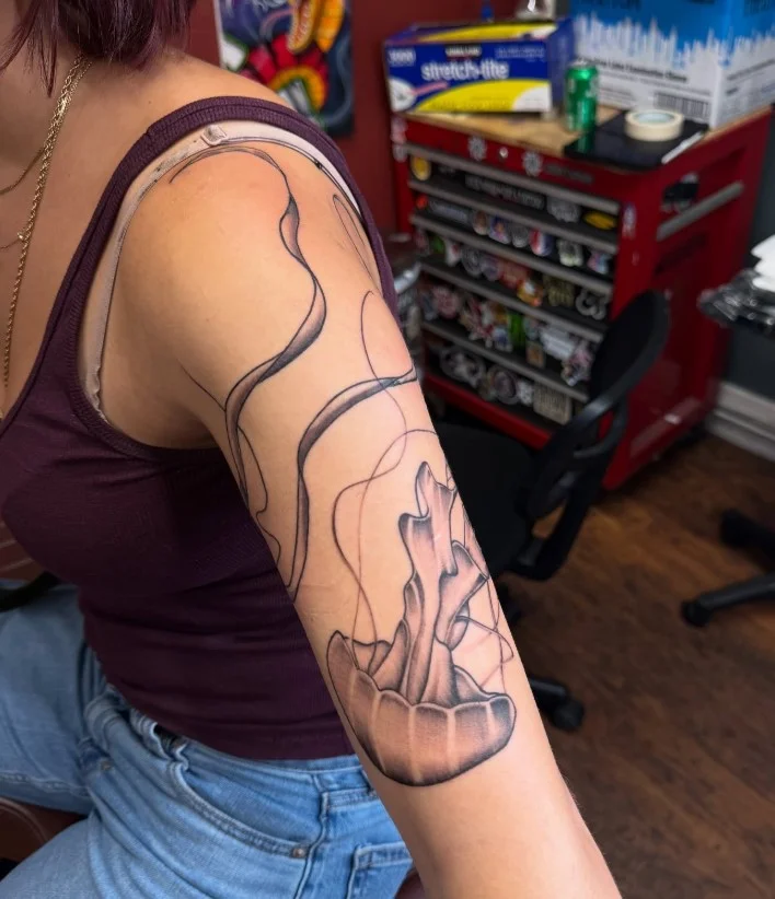 Jellyfish and ocean-inspired arm wrap tattoo with flowing underwater details