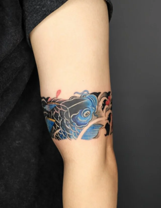 Koi fish and water wave bicep wrap tattoo with flowing aquatic details