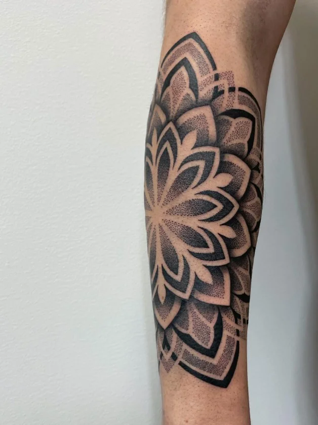Intricate mandala forearm tattoo with symmetrical patterns and fine decorative details