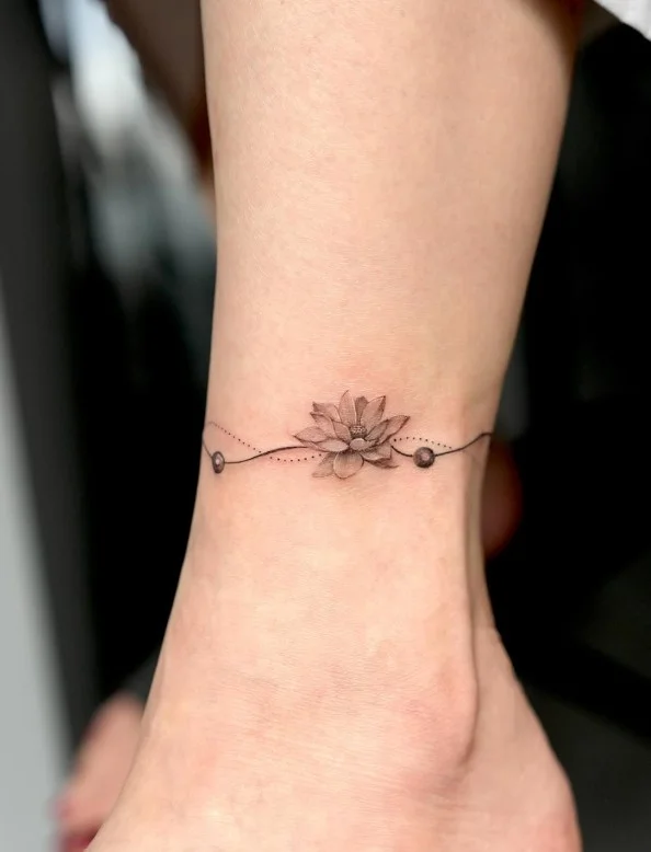 Delicate small ankle tattoo designed as a thin minimalist bracelet wrapping naturally around the ankle