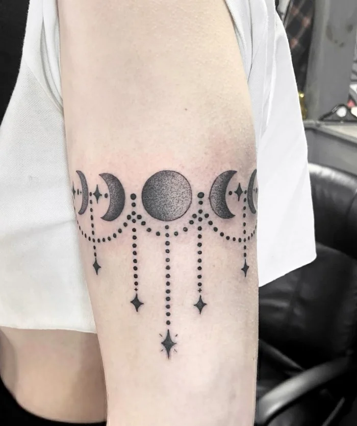 Moon phase and celestial bicep wrap tattoo with moons, stars, and small dots