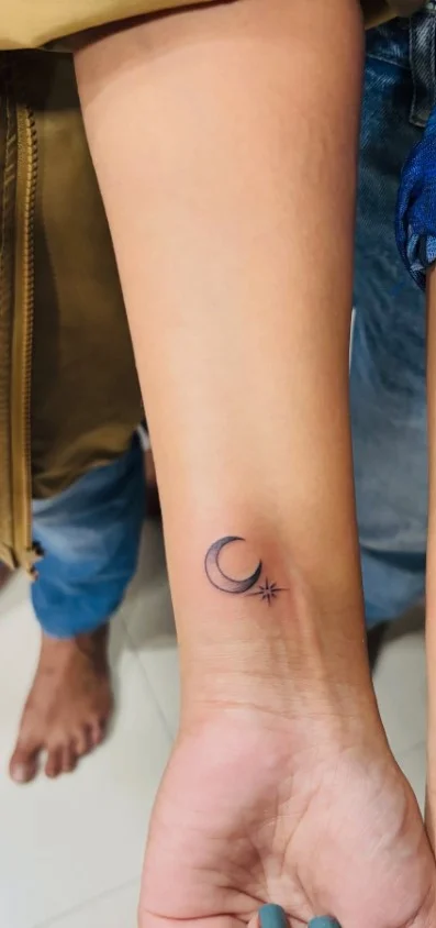 Crescent moon and stars forearm tattoo with delicate celestial details