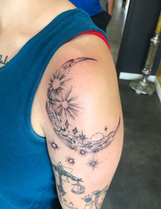 Moon and stars upper arm tattoo with a simple celestial design