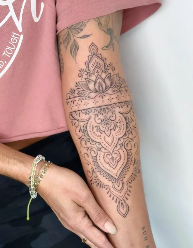 Ornamental mandala tattoo with intricate dotwork on the inner upper arm