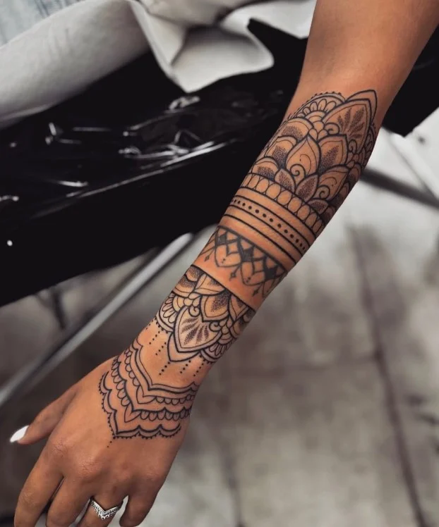 Ornamental mandala tattoo with detailed symmetrical linework on forearm