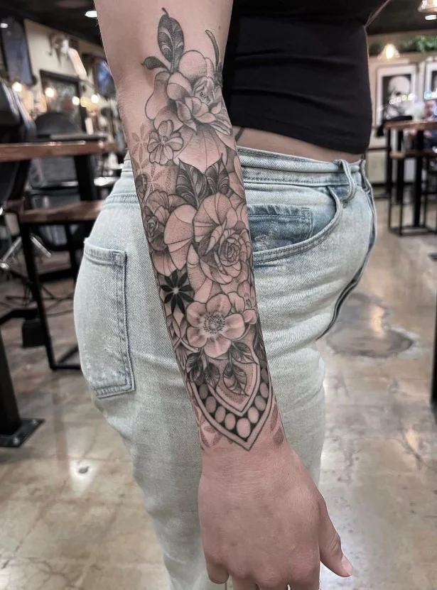 Ornamental wraparound forearm tattoo with curved decorative patterns and fine details