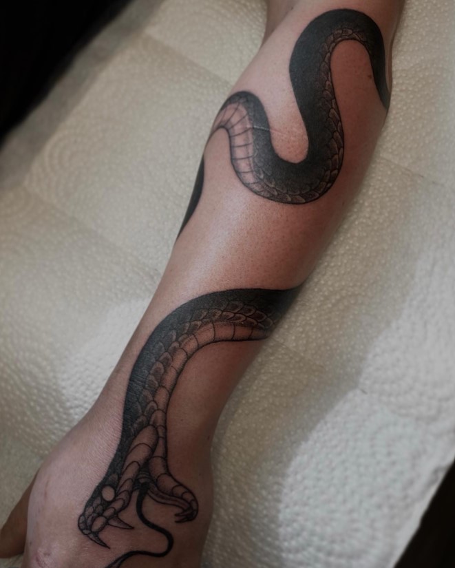 Snake wrapped around arm tattoo with a detailed coiled snake design