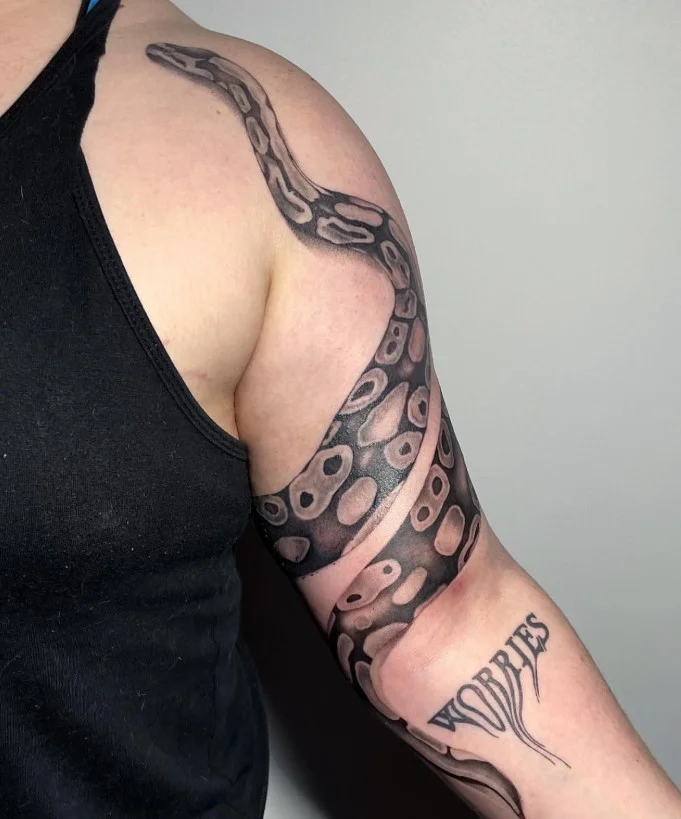 Snake wrapped around bicep tattoo with a detailed coiled snake design