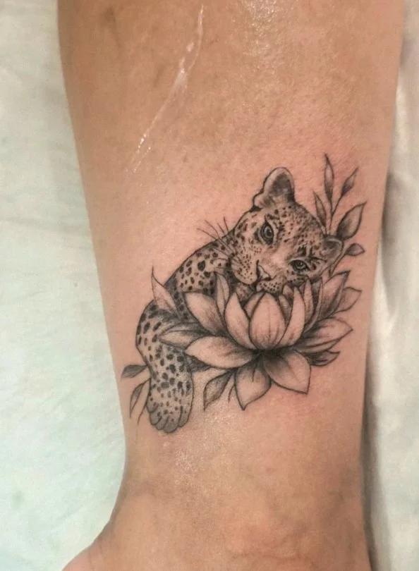 Realistic tiger with lotus flowers in a woman's calf tattoo