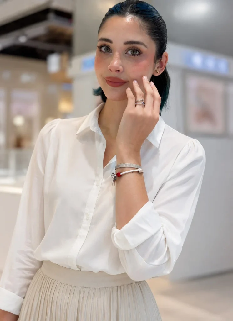 Woman wearing a Pandora bracelet with a white blouse and pleated midi skirt